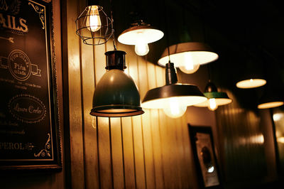 Illuminated electric lamp hanging on wall at home