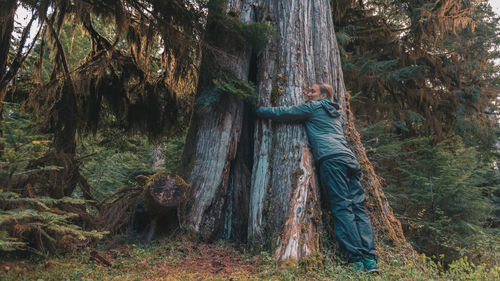 Young woman hugging tree at vancouver island