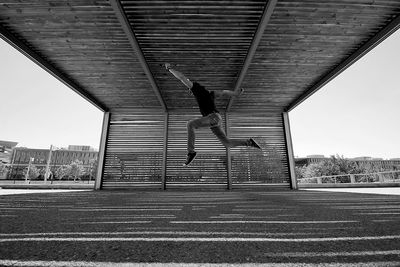 Man jumping below bridge