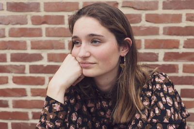 Thoughtful woman against wall