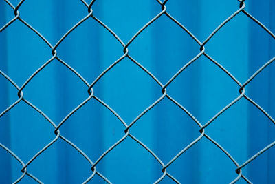 Full frame shot of chainlink fence against blue background