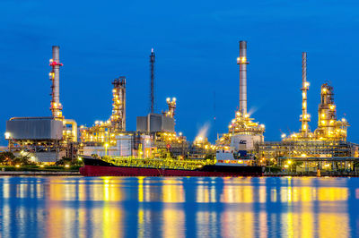 Illuminated factory against blue sky at night