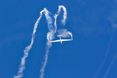 Low angle view of airplane flying against blue sky