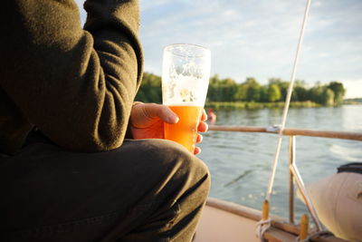 Midsection of man drinking beer from boat