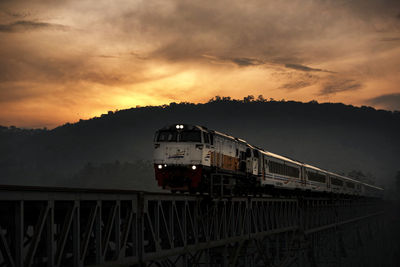 Train on railroad track against sky during sunset