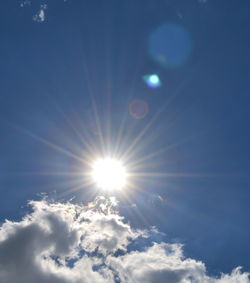 Low angle view of sun shining through clouds