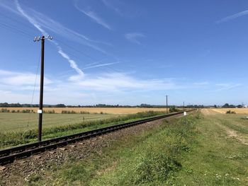 Railroad track amidst field against sky