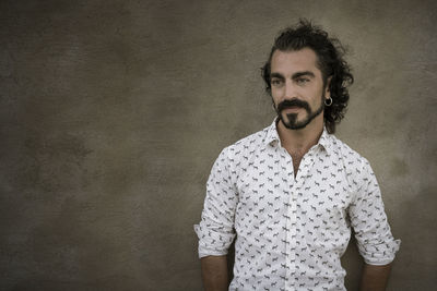 Portrait of young man standing against wall