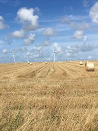 Wind turbines on field against sky