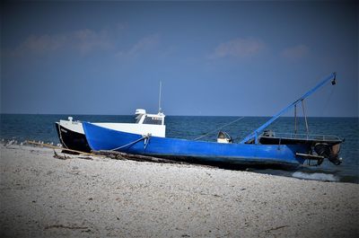 Boat moored on beach against sky