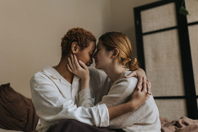 Affectionate non-binary couple sitting at home