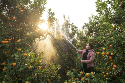 Woman standing by tree against plants