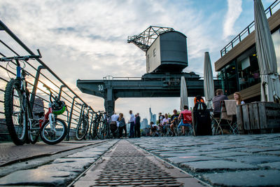 People on bicycle in city against sky