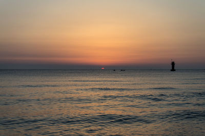 Silhouette man in sea against sky during sunset