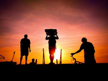 Silhouette people playing against sky during sunset