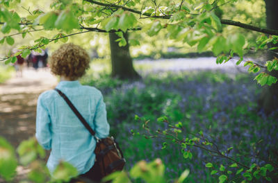 Rear view of woman standing on tree trunk