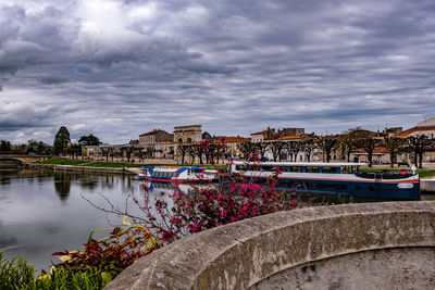 Bridge over river by buildings against sky