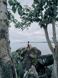 Man standing on rock against sky