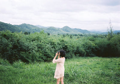 Full length of man photographing on field