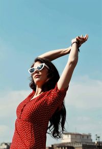 Portrait of young woman standing against sky