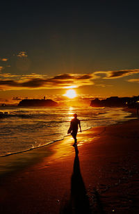 Silhouette man standing on beach against sky during sunset