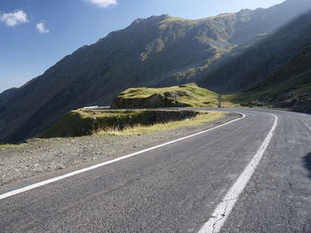 Empty road by mountains against sky