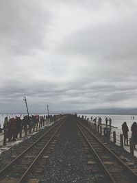 People on railroad track against sky