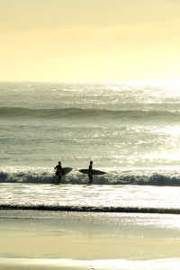 Silhouette people on beach against sky