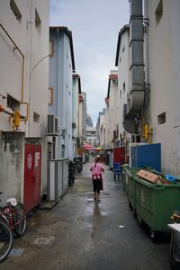Rear view of woman standing on street amidst buildings