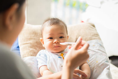 Midsection of woman feeding baby at home