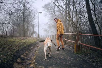 Rear view of man with dog in winter