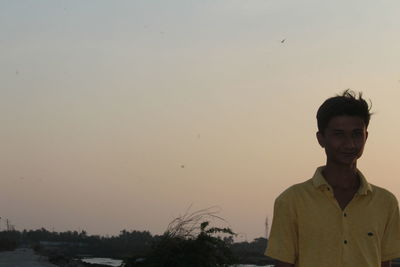 Portrait of young man standing against sky during sunset