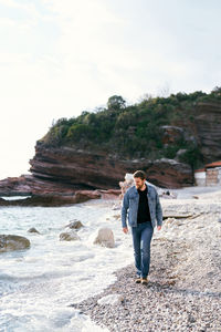 Full length of woman standing on rock against sky