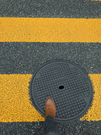 Low section of person standing on yellow road