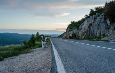 Empty road along trees and plants against sky