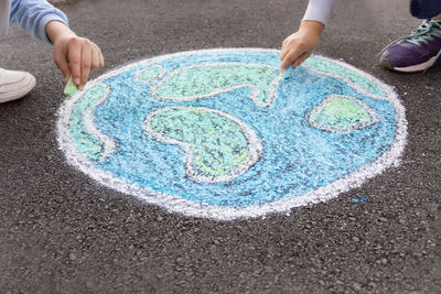 Children draw the planet earth with chalk on the pavement, close up