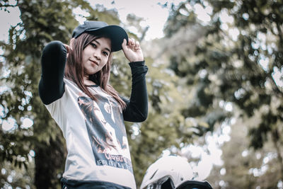 Portrait of smiling young woman standing against trees