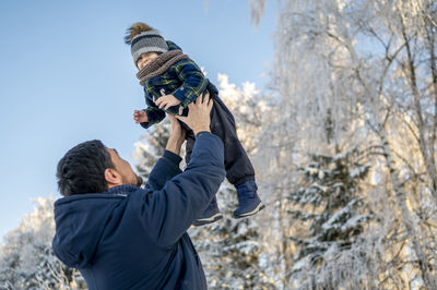 Playful man carrying son in winter park