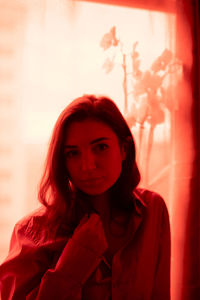 Portrait of beautiful young woman standing against curtain