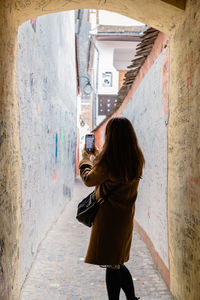 Woman exploring and taking pictures of a narrow street in brasov city, romania.