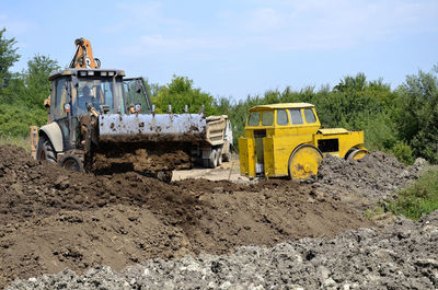 Yellow construction site on field against sky