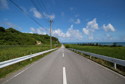 Road amidst green landscape against sky