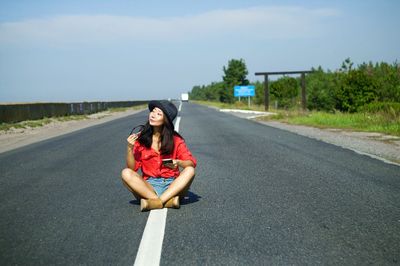 Portrait of woman sitting on road in city