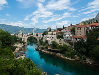 Bridge over river by buildings against sky