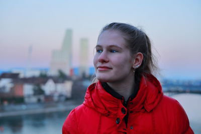 Portrait of young woman standing against river