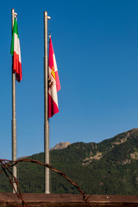 Low angle view of flags against clear blue sky