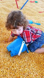 Cute baby boy with toys on corn