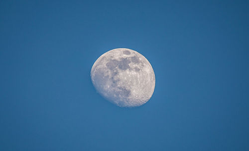 Low angle view of moon against clear blue sky