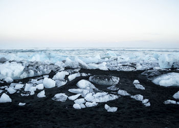 Scenic view of snow covered land and sea against sky