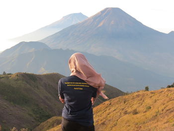 Rear view of woman in headscarf standing on mountain against sky